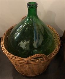 Demijohn Bottle Dark green in color Approximately 4 to 5 gallons in basket that opens freely