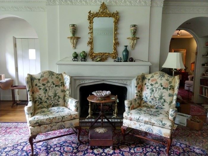 Lovely pair of vintage Hickory Chair wingbacks, with Schumacher fabric, antique English mahogany 3-legged spool table, antique embroidered footrest, antique English brass andirons and fender, ornate Italian gold gilt mirror, with cloisonne collection on mantle. 