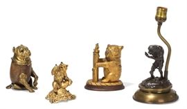 Lot 44 A group of four table decorations 
20th century 
Comprising a brass and wood inkwell in the form of a seated dog; a gilt bronze inkwell in the form of a bear; a gilt metal model of a seated bear and a patinated bronze and brass table lamp centered by an ape and a serpent. 