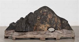 Lot 102 A Lingbi 'Contemplation' stone on stand 
overall height 15 1/2in (39.25cm); length 32 1/2in (82.5cm); width 10in (25.5cm) 