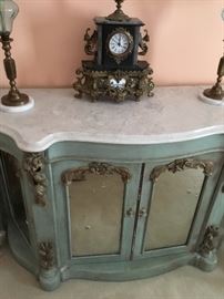 Antique marble top cabinet, antique clock, and a pair of lamps.