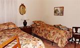 Twin beds with matching comforter sets, side table, chairs, gilt mirror, quilts.