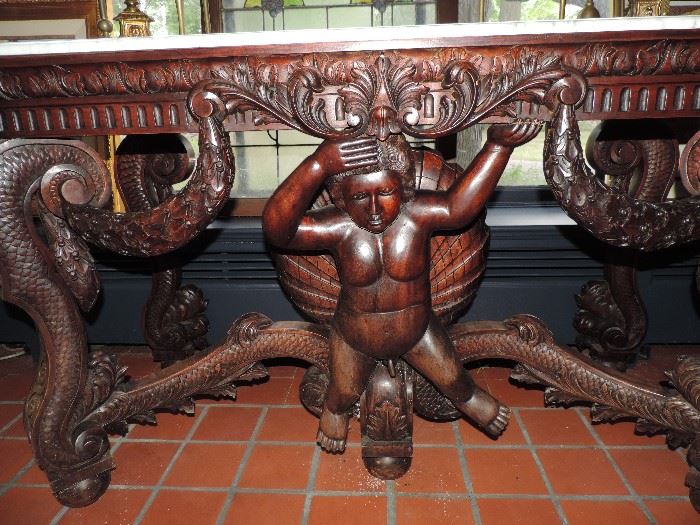 Large carved wood table with putti, scrolling swags and fish-scale details overall - marble top - late 20th century.
