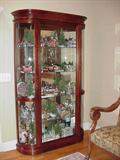 Lighted curio containing many collectibles including Dickens Village, Byers, Heritage Village