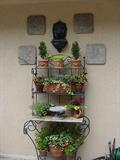 Baker's rack with lots of potted containers, plaques, and lavabo