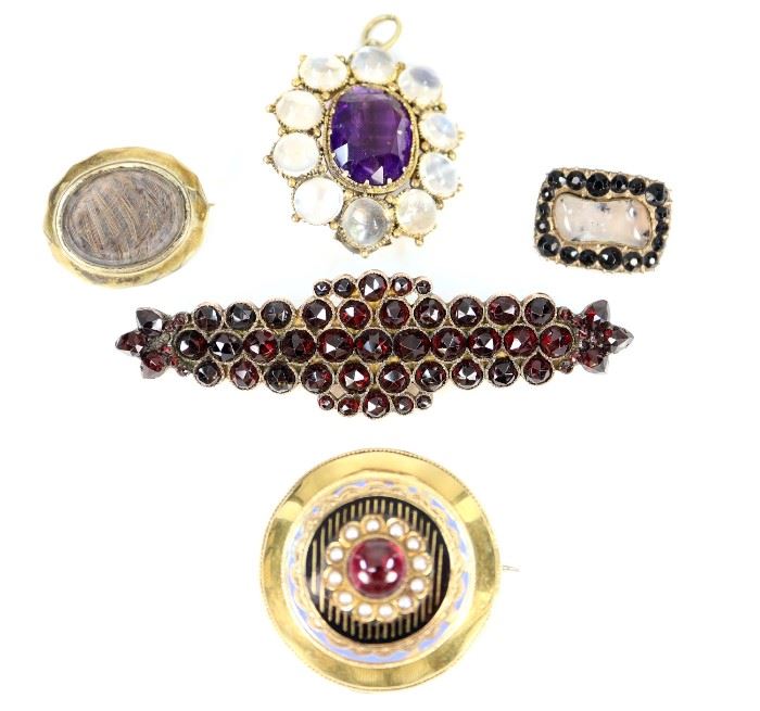  A Group of Five 19th Century Brooches -  Including 1 jet and moss agate pin, engraved and dated 1817, 1 small mourning brooch, 1 amethyst and moonstone pendant/brooch, 1 Victorian garnet brooch, and 1 Late 18-Early 19th Century European gold brooch/locket with enamel decoration that is centered by a garnet cabochon and twelve seed pearls, stamped with two faint markings at the clasp.  Wear to each piece, the gold brooch/locket has some misshapen portions around the edge, the Victorian garnet brooch lacks the pin.  Up to 2 3/4" long.  Totaling 32.5 grams. 
