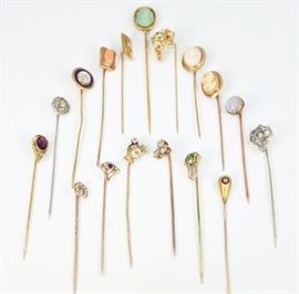Seventeen 19th Century Stick Pins - Consisting of fourteen pins marked "10 k" with various enhancements including: moonstone, cameo shell, seed pearls, diamonds, and other gemstones. Together with three other unmarked stick pins,  which feature treble cleft note with diamond, carved scarab, and leopard with diamond and emerald chips. Wear noted overall, one pin lacks the solitaire center stone, some pins are bent or misshape, and the scarab is cracked. Up to 3.25" long. Totaling 28.8 grams.