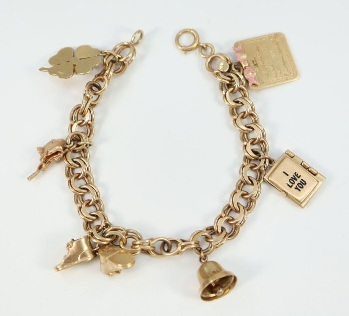 A 14 kt Yellow Gold Charm Bracelet -  Bracelet hung with 6 charms including a Birth Certificate, a Marriage License, a bell, baby booties, a swimsuit, and a shamrock with pearl accent.  Bracelet and charms are all stamped "14K".  Some wear/scratches noted.  7 1/4" long.  Totaling 30.8 grams.  