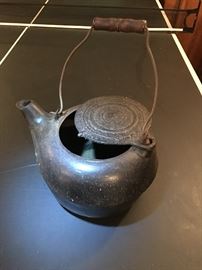 Cast iron tea kettle with lid that slides to the side.