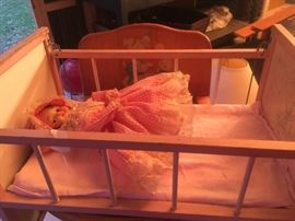 Wooden doll crib with one side that actually comes down with metal bar simulates a real crib it is pink & cream in color