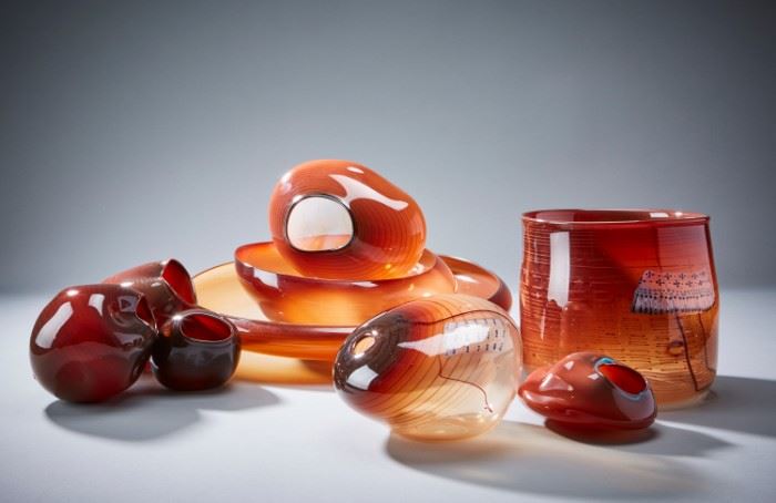 Lot #40 Dale Chihuly (b. 1941). Nine amber glass baskets of varying sizes and shapes. Largest signed and dated 1980 along the base.
Provenance: Private collection, Chicago, Illinois.
Biography: Dale Chihuly first encountered glass art as an interior design student at the University of Washington. Immediately fascinated, he went on to study glass at the University of Wisconsin, which was the first university in the United States to teach glassblowing. From there, he went on to the Rhode Island School of Design, where he continued to learn about glass and eventually ended up teaching. His education continued with a Fulbright Fellowship to go to the famous glassblowing studios of Venice. After his time in Italy, he returned to his home state of Washington to found his own glass school, the Pilchuck Glass School, with Ann and John Hauberg, influential supporters of the arts in Seattle. At this school, his art style and process truly flourished. In particular, Chihuly first fostered the col