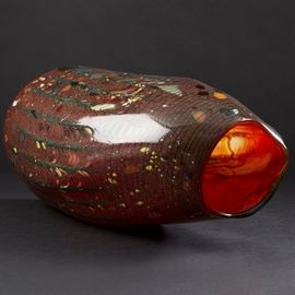 Lot #41 Dale Chihuly (b. 1941). Cylindrical glass vase with rippled sides. Signed and dated 1981 along the base. 
Provenance: Directly from artist.
Collection of Edward Claycomb.
Biography: Dale Chihuly first encountered glass art as an interior design student at the University of Washington. Immediately fascinated, he went on to study glass at the University of Wisconsin, which was the first university in the United States to teach glassblowing. From there, he went on to the Rhode Island School of Design, where he continued to learn about glass and eventually ended up teaching. His education continued with a Fulbright Fellowship to go to the famous glassblowing studios of Venice. After his time in Italy, he returned to his home state of Washington to found his own glass school, the Pilchuck Glass School, with Ann and John Hauberg, influential supporters of the arts in Seattle. At this school, his art style and process truly flourished. In particular, Chihuly first fostered the collabo