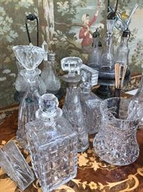 Waterford, Shannon and various crystal decanters and cruet sets, atop an inlaid Venetian wood round bar cart. 