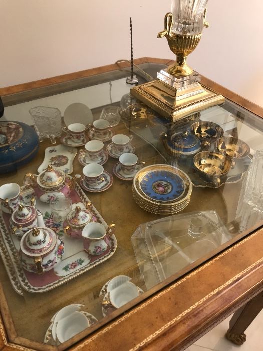 Limoges and Bavarian porcelain children's tea service shown within figural gilt and glass horizontal curio table. 