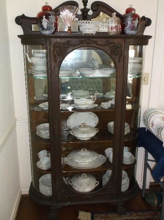 Ornate oak curved glass china cabinet w/Limoges china including great serving pieces