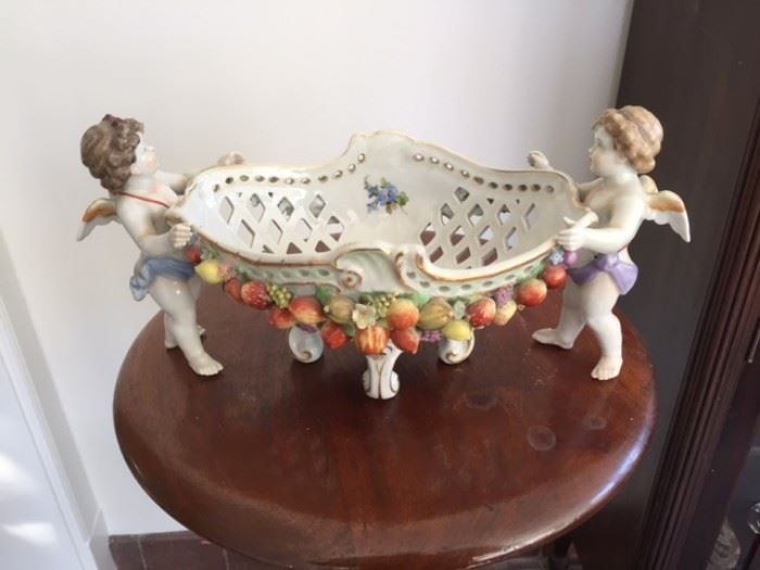 Polychrome German porcelain openwork bowl supported by standing winged putti. 