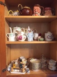 A ktichen cupboard, full of vintage kitchen ceramics, including Royal Doulton mugs.