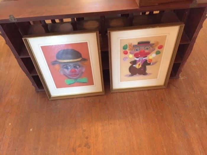 Framed chalk drawings of two clowns.
