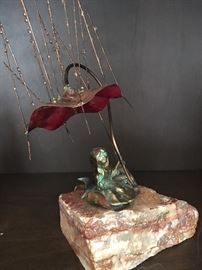 Enchanting fairy with umbrella metal sculpture on marble.