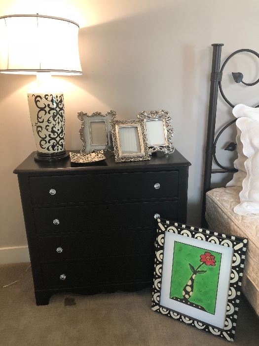 Dresser/nightstand with black and cream lamp, picture frames, framed print - and view of king bed frame!