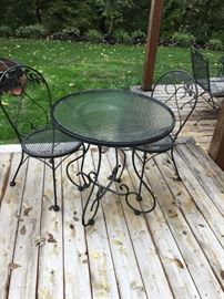 Adorable bistro wrought iron table with glass top and two chairs.