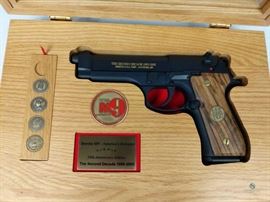 Beretta M9 Commemorative / Defender 1985-2005 2nd Decade, commemorative pistol. Never fired. Black with gold lettering. Solid wood grips. Solid wood display case includes 1 Beretta M9 Challenge coin, and 4/5 Military branch mini-coins (Army. Navy, Marines, Air Force - no Coast Guard). Solid wood/glass display case in excellent condition. 9mm, FFL #273
