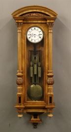 Vienna Regulator - A late 19th century three weight Vienna Regulator wall clock. 8-day time and strike movement with two part porcelain dial and quarter hour Grand Sonnerie striking on two wire gongs, "Compensating" pendulum and matching etched weights. Walnut case with molded arched crown over a single long door with fluted pilasters and carved detail. Older refinishing with minor wear. Running when cataloged. 53 1/2" high overall.