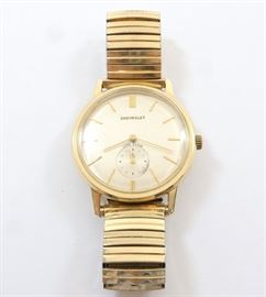 14k Gold Lord Elgin "Chevrolet" Wristwatch - "Chevrolet" 25 years of service wristwatch. 23 j, 730 cal. mvt, Adj 6 pos, manual wind, 34mm Star Watch Case Co. 14k Yellow Gold case. Champagne dial w/Gold baton markers and hands, "Chevrolet" in Gold letters. Serial #T714312. 53.2 grams total weight. Minor wear, engraved rear cover, replaced band. Winds, sets and running when cataloged.