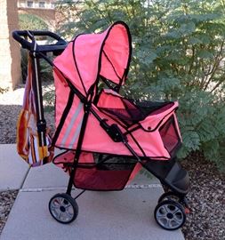 A PRETTY HOT PINK DOGGIE STROLLER! And hanging on the stroller is a fabric doggie carrier.