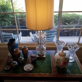 Asian items, crystal lamp, crystal vases and painted glass covered jar, all on a table with leather top