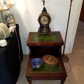 French ? clock on leather top step table (one of two). Art glass vase and oval covered box