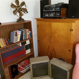 Piano roll cabinet, books, vintage speakers, and an older stereo on top of cabinet.  Fan is an oldie!