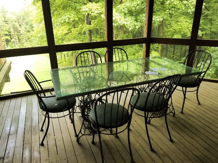 Unique glass topped table with two treadle sewing machine bases and six ovely black metal ice cream chairs 