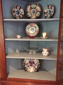 Interior of corner cupboard. Included are Imari plates & Steuben pieces.