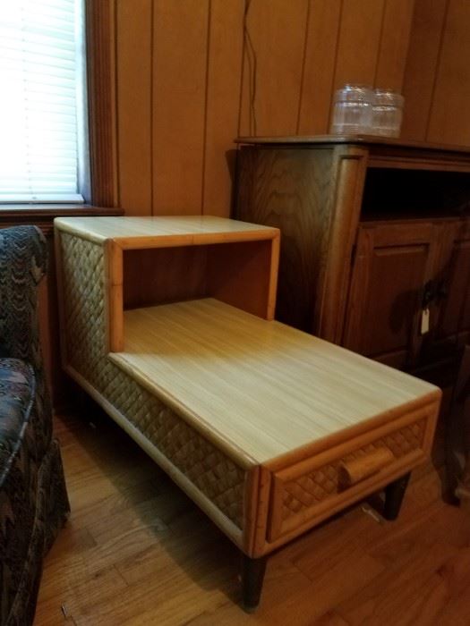 Mid-century modern end table with tapered legs and a drawer. Cane lattice side details.