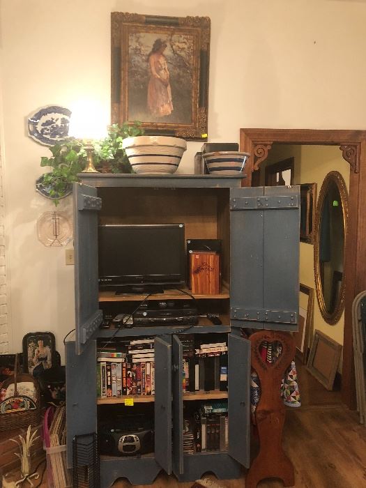 painted wood cabinet, flat screen tv, mixing bowls, VHS player, VHS tapes