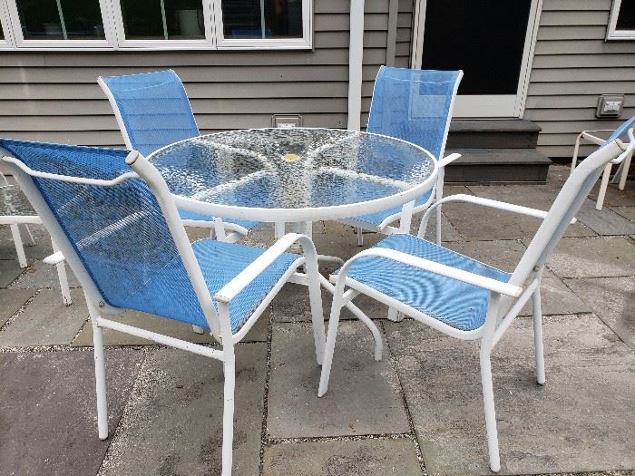 Round glass top table with 4 blue sling chairs. 