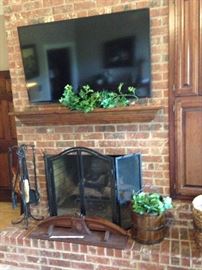 Black fireplace tool and screen; large TV; wooden bucket planter; antique shelf