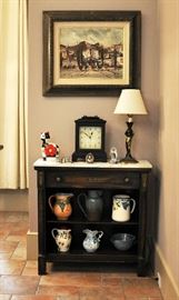 A more vintage shelf with a marble piece on top holds a collection of pitchers, one of many, many contemporary designer clocks and an original painting from Spain.