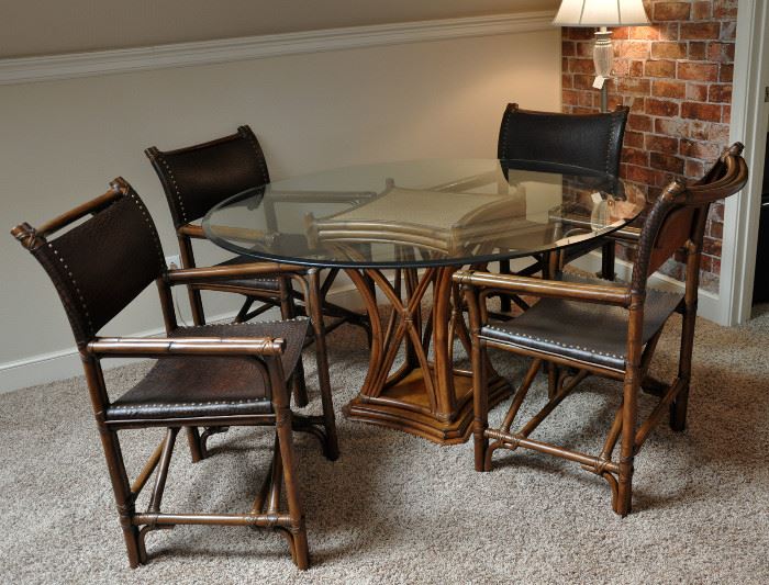 The upstairs den has a round beveled glass table and for chairs in wood that is designed like rattan.  The campaign style chairs have an embossed or printed leather.  The entire set is in as new condition.