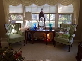 Pair of mint channel back chairs and sofa table with Blenko glassware collection.