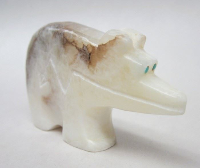 White onyx bear fetish figure. Inlaid eyes, deer, arrow and bear paw inscribed on sides. Signed "RL" in pen on underside of foot. 2 5/8" wide