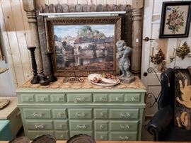 Large vintage refinished dresser, candle holders, serving dishes, cherub figurine, picture, and headboard.