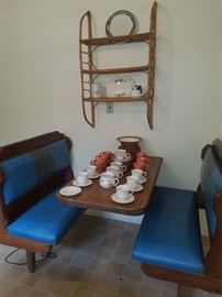 Wooden seats/table restaurant booth. Vintage. Wicker shelf. Dishes including Homer Laughlin cups/saucers, Cyclamen pottery cups & plates.