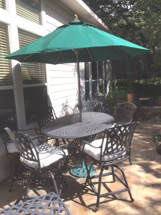 Photo of black metal rectangular table with six swivel armchairs, market umbrella and metal stand.