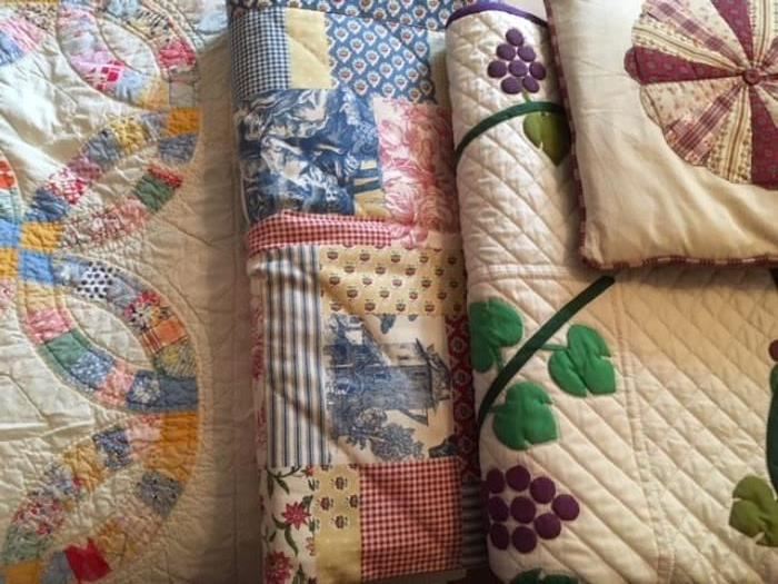 Several modern, handmade quilts and wall hangings, as well as antique quilts