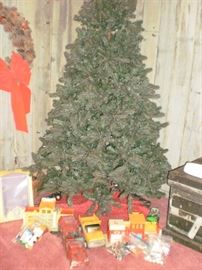 Rotating Christmas tree with vintage fisher price items and two metal trucks underneath on the skirt.