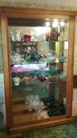 Beautiful curio cabinet containing vintage Fenton glass baskets and other glassware.