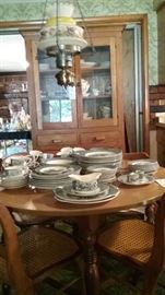 Currier and Ives dinnerware.  Oak hutch and caned oak chairs.