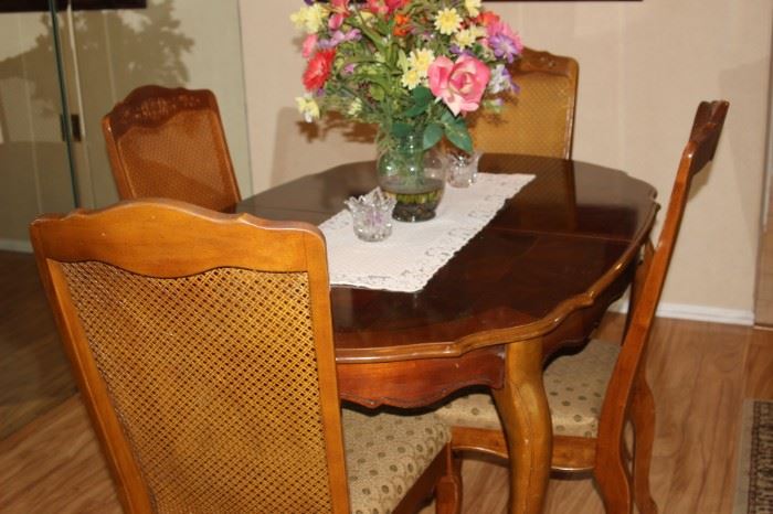Dining table with cane back chairs, pads and leaves.